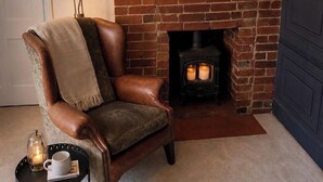 A leather armchair with a throw blanket, a fireplace with two candles, and a tray with a mug and candle. - Three-bedroom house in Exmouth, sleeps 6 (Exmouth)