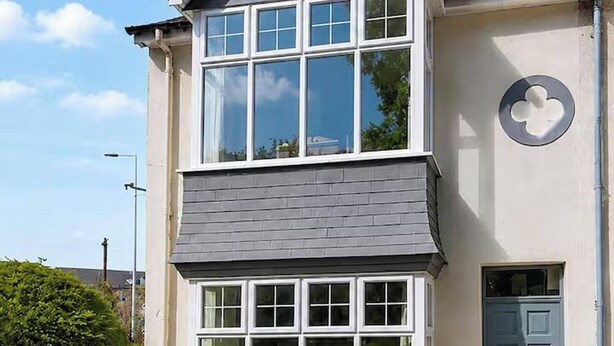 A two-story building with a grey shingled roof, white-framed windows, and a blue door. - Three-bedroom house in Exmouth, sleeps 6 (Exmouth)
