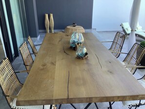 Ein Holztisch mit Korbstühlen, einem gewebten Pouf und Glaswindlichtern.