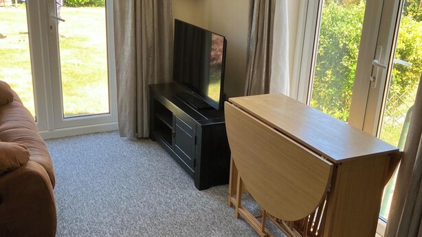 Una habitación con sofá, mueble para televisión y una mesa de madera.