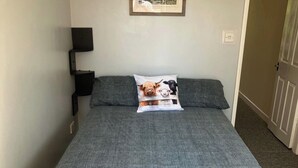 Una cama con una manta gris y un almohadón con diseño de perro y vaca.