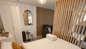 Et moderne soveværelse med en stor seng, en trævæg, et spejl og et skrivebord med en lampe.