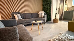 En moderne stue med en grå sofa, et rundt sofabord og en pelsløber.