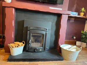 A fireplace with a modern design, flanked by two buckets of firewood. - Cozy Cottage Retreat near Haworth, log burner (Keighley)