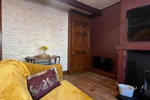 A cozy living room with a stone wall, wooden door, and fireplace. - Cozy Cottage Retreat near Haworth, log burner (Keighley)
