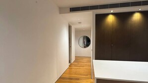 A hallway with wooden flooring, a white wall, and a dark wooden cabinet with a mirror. - 2B2B Executive Residence in Barton, 7-9 min walk to PH, M-Oval & Lake BG (Barton)