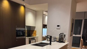 A modern kitchen with a central island, wooden stools, and a coffee machine. - 2B2B Executive Residence in Barton, 7-9 min walk to PH, M-Oval & Lake BG (Barton)