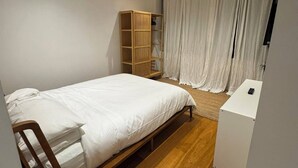 A bedroom with a wooden bed, a white bedside table, a wardrobe, and a curtain. - 2B2B Executive Residence in Barton, 7-9 min walk to PH, M-Oval & Lake BG (Barton)