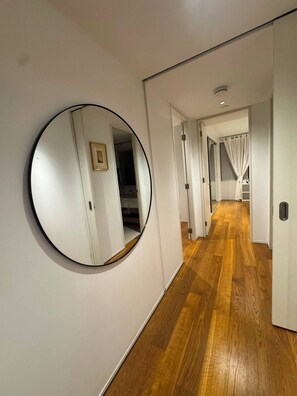 A hallway with a round mirror on the wall, wooden flooring, and doors leading to other rooms. - 2B2B Executive Residence in Barton, 7-9 min walk to PH, M-Oval & Lake BG (Barton)
