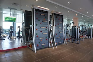 Ein Fitnessstudio mit Laufbändern, Steigern und einer Kletterwand.