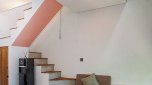 Un interior moderno con una escalera, un sofá, una mesa de centro y un refrigerador.