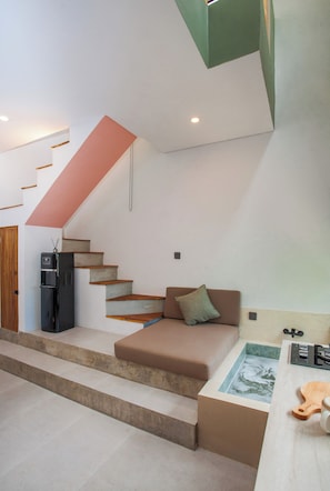 A modern interior with a staircase, a sofa, a coffee table, and a refrigerator.