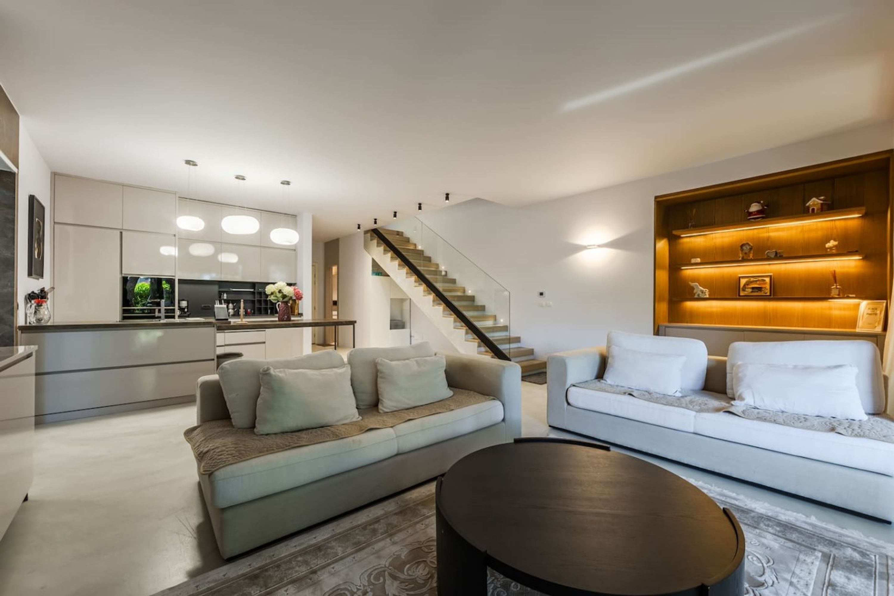 Una sala de estar moderna con un sofá, una mesa de centro y una escalera que sube a un nivel superior.