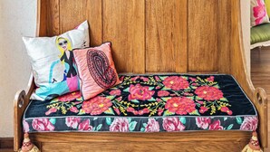 A wooden bench with floral upholstery, a wall with ornate golden frames, and a television. - Boutique Hacienda Design and Comfort (Juriquilla)