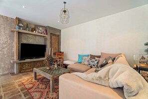 A living room with a sofa, television, decorative items, and a patterned rug.