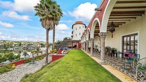 A hotel corridor with a view of the city, palm trees, and a fountain. - Boutique Hacienda Design and Comfort (Juriquilla)