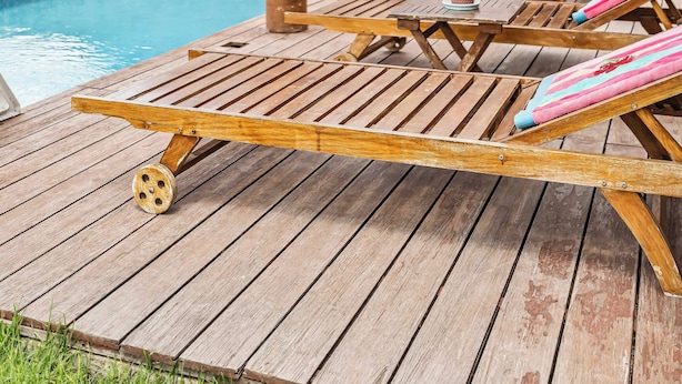 A wooden deck with lounge chairs, a pool, and a stone wall. - Boutique Hacienda Design and Comfort (Juriquilla)