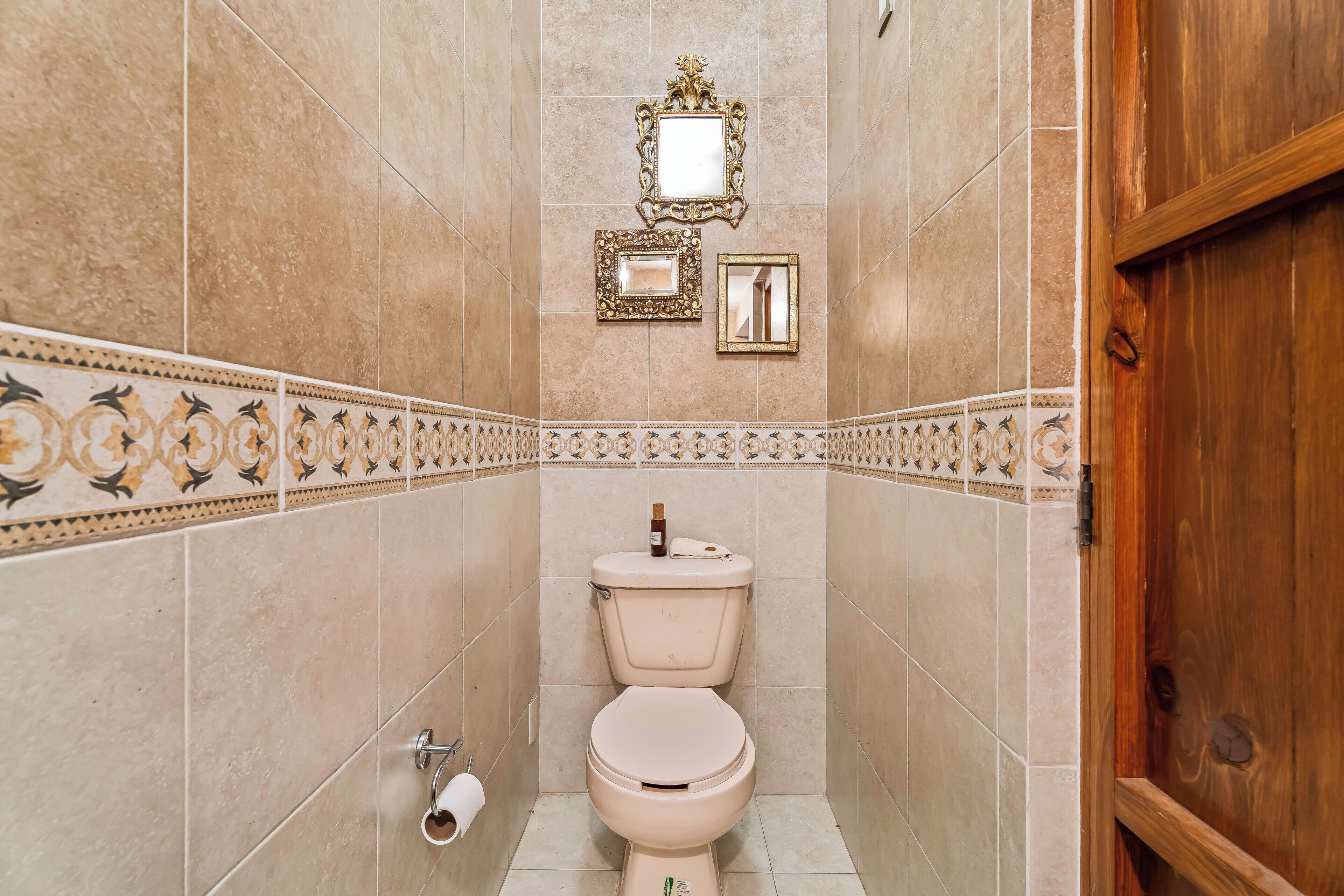 A bathroom with a toilet, a mirror, and a decorative tile border.