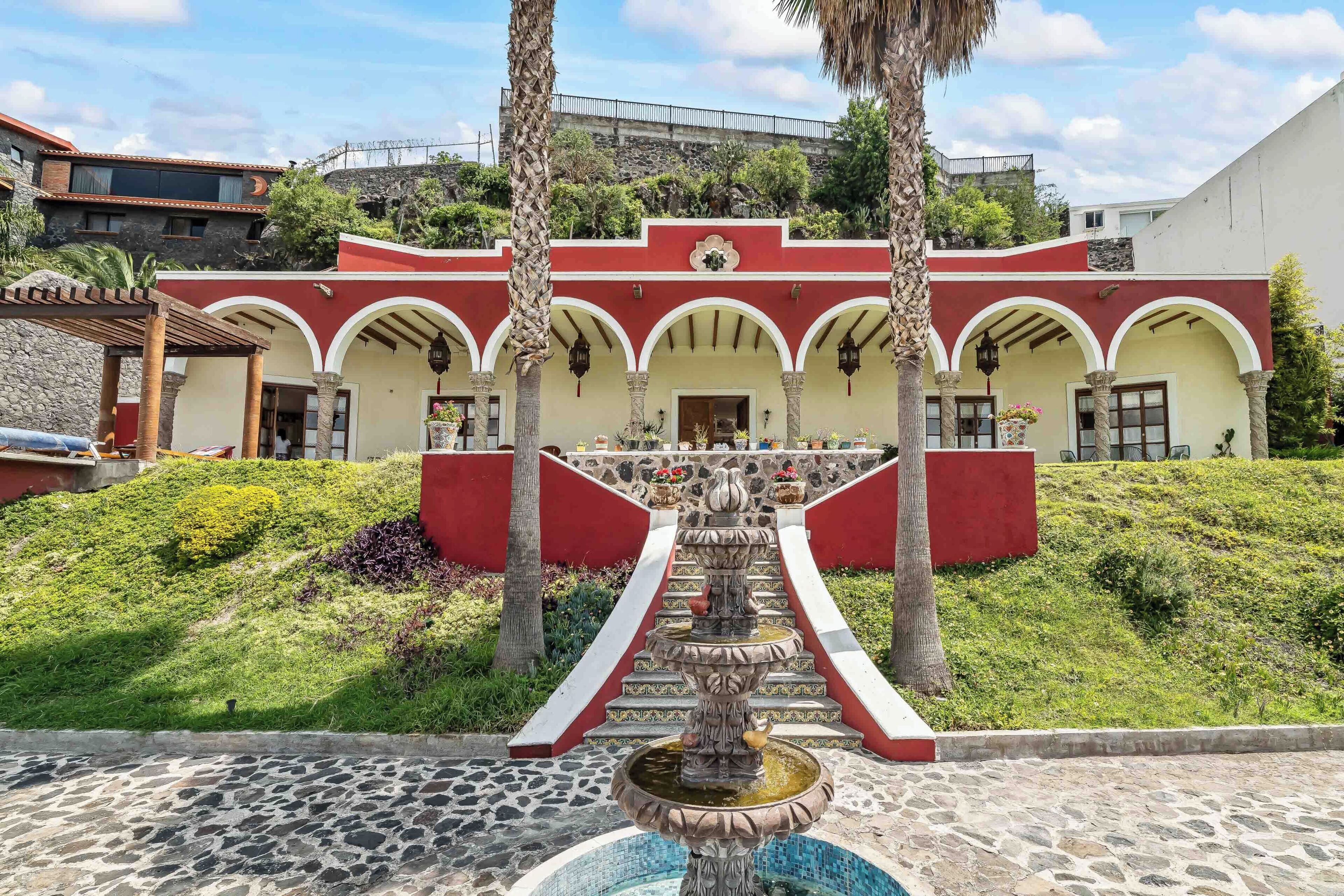 A building with a red and white facade, a central fountain, and a stone-paved courtyard.