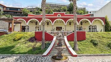 A building with a red and white facade, a central fountain, and a stone-paved courtyard.
