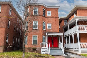 A brick building with a red door and white railings, featuring a small porch and steps leading to the entrance. - The Red Door Retreat - Walking Distance to Downtown Hartford (Hartford)