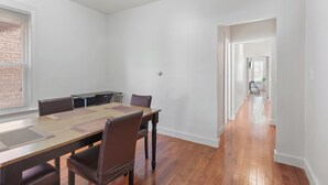 A spacious room with a long wooden table and chairs, a brick wall, and a view through a window. - The Red Door Retreat - Walking Distance to Downtown Hartford (Hartford)