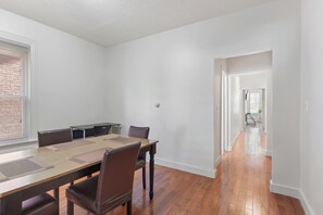 A spacious room with a long wooden table and chairs, a brick wall, and a view through a window. - The Red Door Retreat - Walking Distance to Downtown Hartford (Hartford)