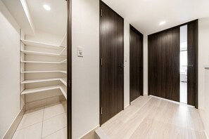 Ein Flur mit Treppe, dunklen Holztüren und hellen Fliesenböden.