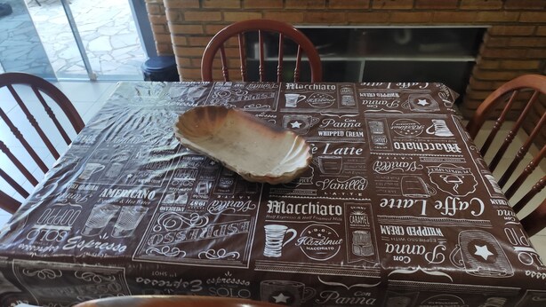 Ein Esstisch mit einem kaffeebezogenen Tischläufer, umgeben von Holzstühlen.