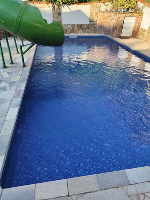 A swimming pool with a green slide, stone walls, and a tiled deck. - Beautiful country house in the Porta do Sol gated community. (Mairinque)