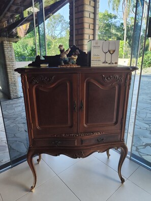 A wooden cabinet with ornate carvings and a box of white wine glasses on top. - Beautiful country house in the Porta do Sol gated community. (Mairinque)