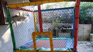 Ein eingezäunter Spielbereich mit Trampolin und kleinem Pool.