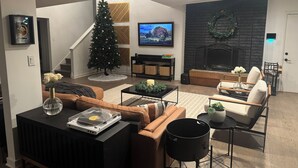 Een moderne woonkamer met een open haard, een kerstboom en een televisie.