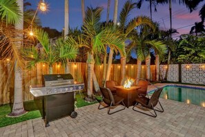 A patio with a grill, chairs, and a fire pit. - Spacious 5BR Heated Pool Villa · minutes to Beach (Hollywood)