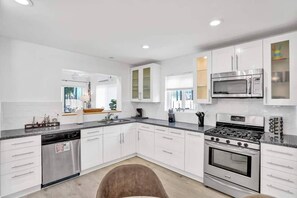 A modern kitchen with white cabinetry, stainless steel appliances, and a central island. - Spacious 5BR Heated Pool Villa · minutes to Beach (Hollywood)