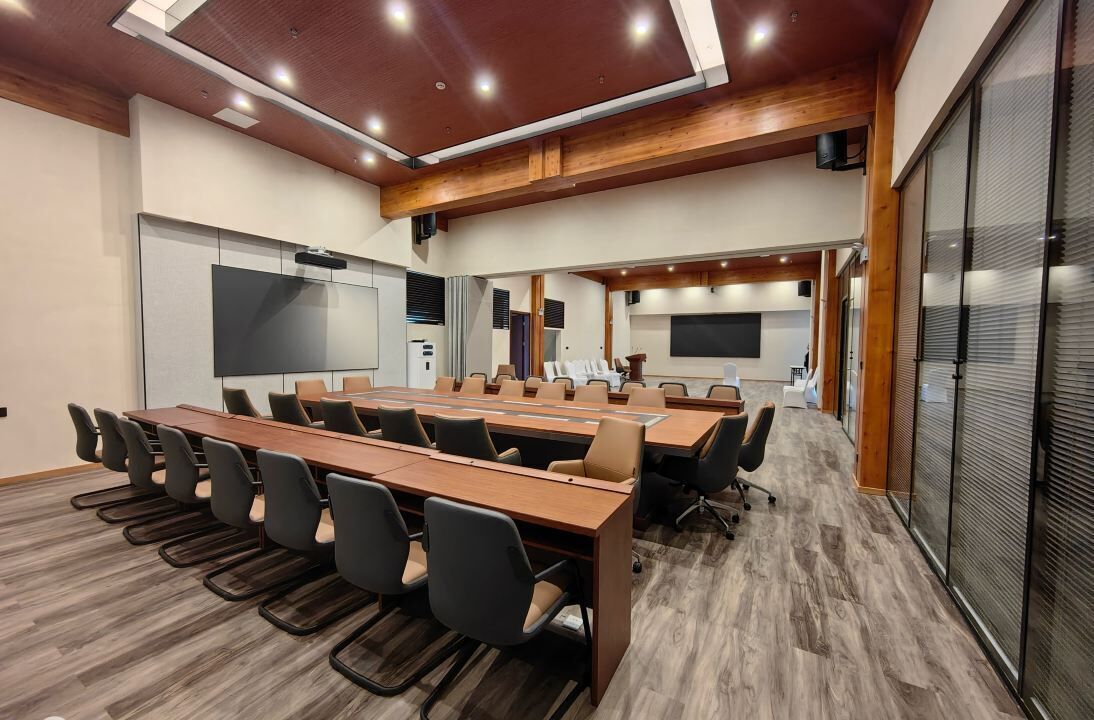 A conference room with a long table, chairs, a projector screen, and a whiteboard.