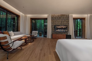 Una habitación de hotel moderna con una cama grande, un sofá, una mesa de comedor y una chimenea.
