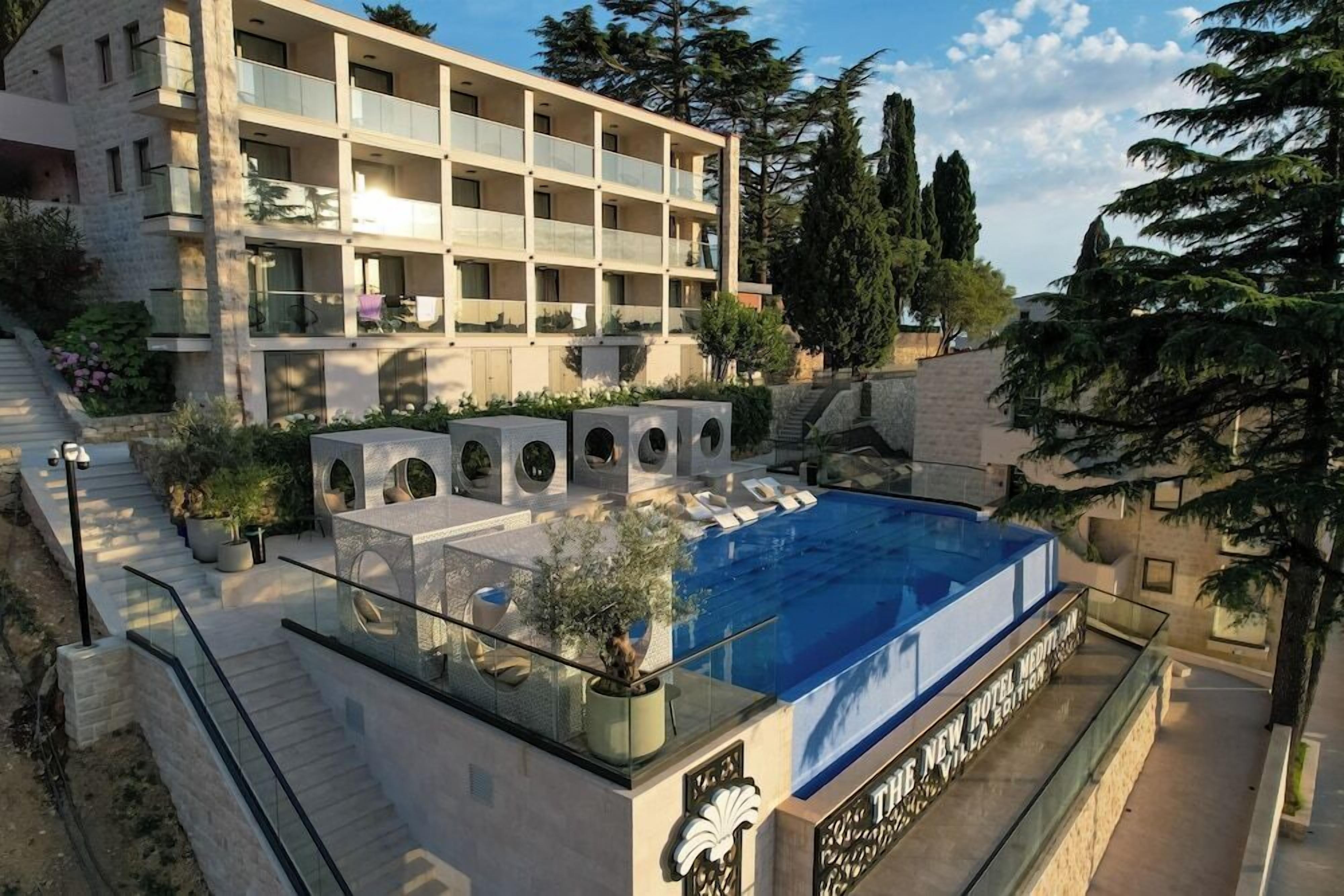 Un hôtel à plusieurs étages doté d’une piscine sur le toit, d’un espace extérieur aménagé et d’un jardin paysager.