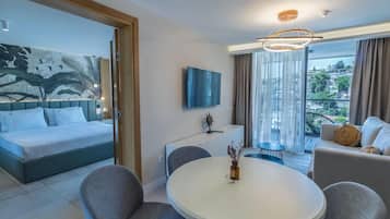 A hotel room with a bed, a dining table, a sofa, a TV, and a balcony with curtains.