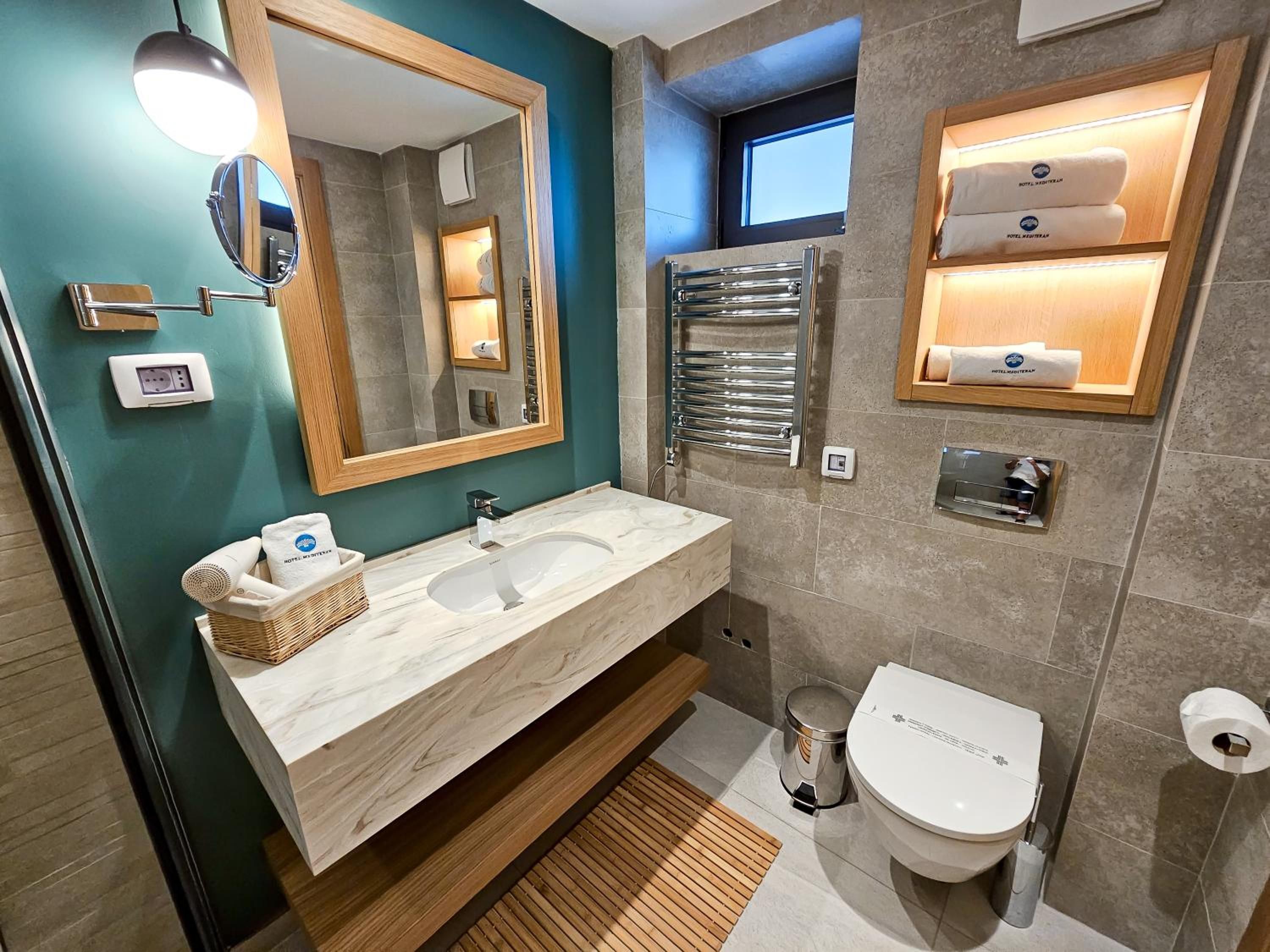 A modern bathroom with a marble sink, a mirror, a towel rack, and a toilet.