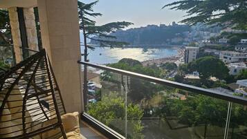 A balcony with a view of a coastal cityscape, including a beach and buildings.