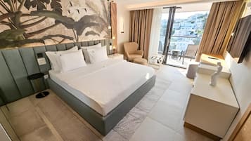 Ein modernes Hotelzimmer mit einem großen Bett, einem Schreibtisch, einem Sessel und einem Balkon mit Blick.