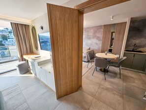 Eine moderne Küche mit Holzwand, ein Essbereich mit rundem Tisch und Stühlen sowie Blick auf die Stadt durch große Fenster.
