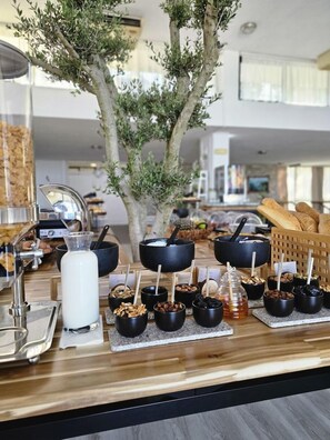 Mesa de buffet con diversos alimentos y un árbol al fondo.