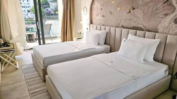 Quarto de hotel com duas camas, varanda e vista, e cabeceira decorativa.