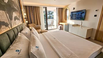 Ein Hotelzimmer mit einem großen Bett, einem Schreibtisch, einem Sessel, einem Fernseher und einem Balkon.