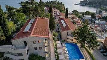 A coastal hotel with a swimming pool, terraced balconies, and a view of the sea.