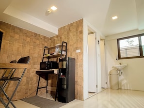 A compact kitchen with a microwave, a coffee machine, and a small shelf unit. - Jamjun Hostel Sukhumvit (Bangkok)