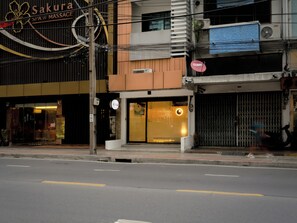 A building with a spa and massage service, a closed shop with a sign, and a street with a pedestrian crossing. - Jamjun Hostel Sukhumvit (Bangkok)
