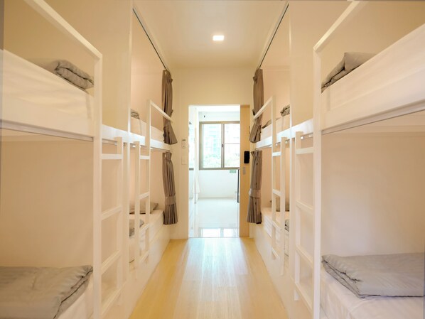 A corridor with bunk beds, a door at the end, and a window with daylight. - Jamjun Hostel Sukhumvit (Bangkok)